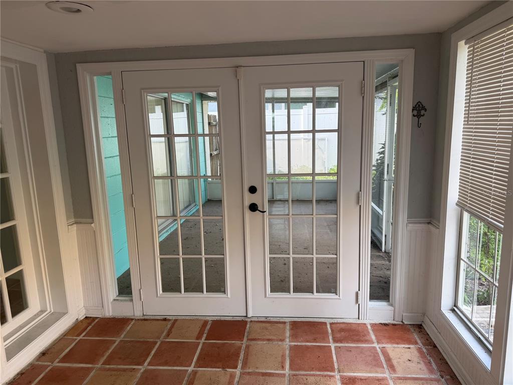 A sunroom features terracotta tile flooring, white French doors, and a window with blinds — 9830 MARK TWAIN LANE, PORT RICHEY, FL