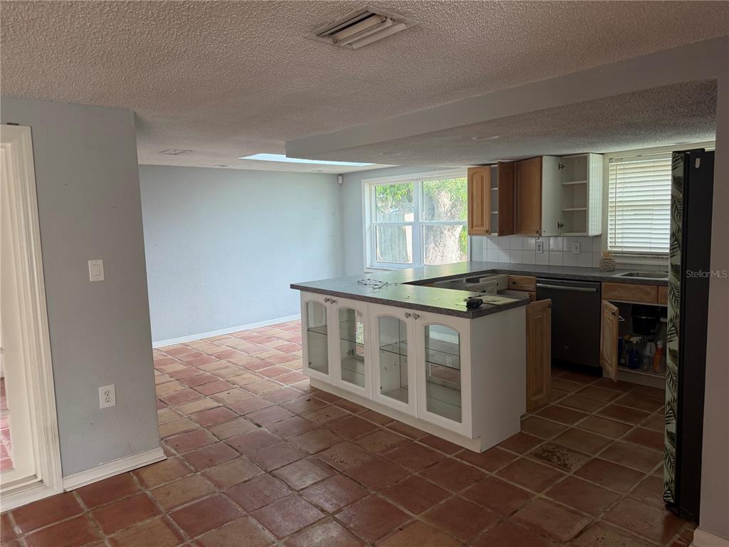 A kitchen with a peninsula, light-colored walls, and terracotta tile flooring — 9830 MARK TWAIN LANE, PORT RICHEY, FL