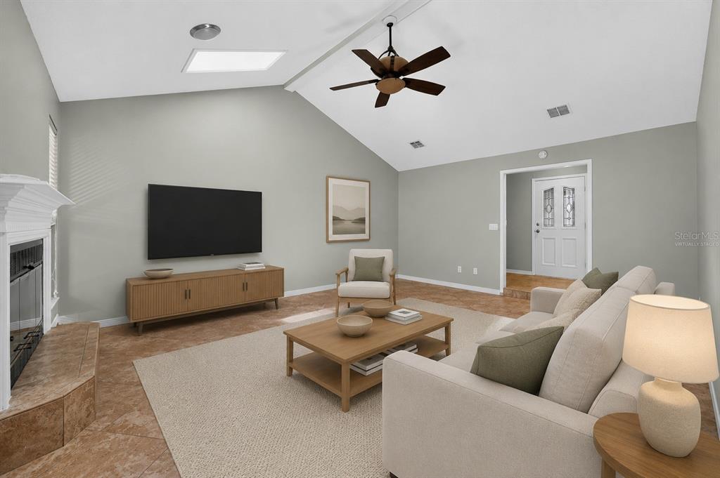 A virtually staged living room features a vaulted ceiling, fireplace, tile flooring, and a ceiling fan — 3080 MARRANO DRIVE, ORANGE PARK, FL