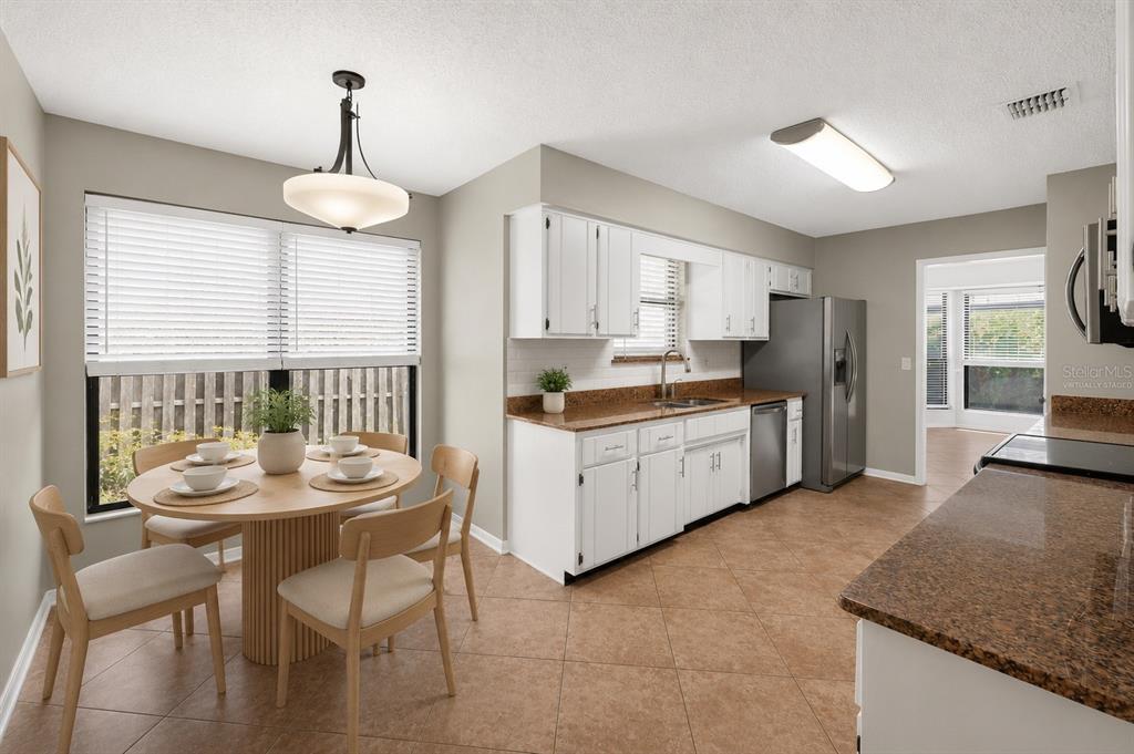 A kitchen with white cabinets, brown granite countertops, and a round dining table with chairs — 3080 MARRANO DRIVE, ORANGE PARK, FL