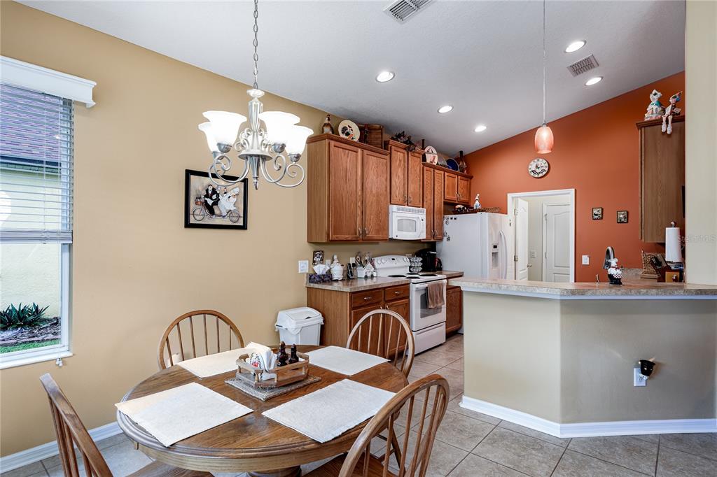A kitchen with wood cabinets and a round dining table sits adjacent to a counter — 3628 101ST AVENUE E, PARRISH, FL