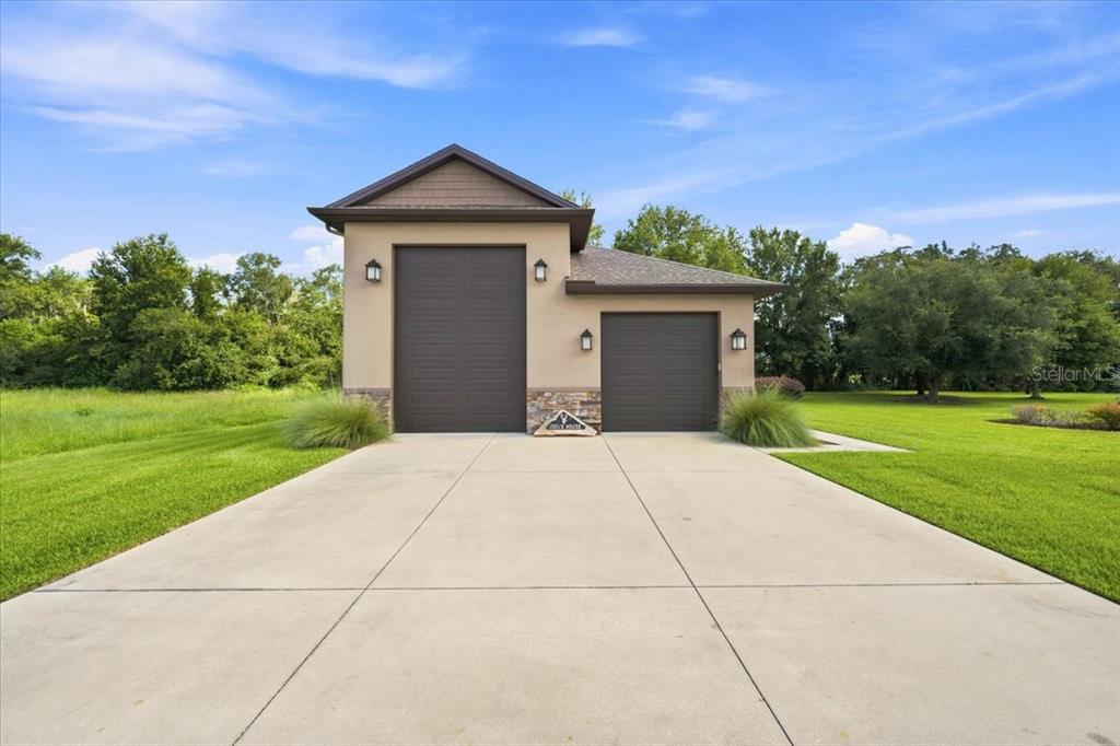 A detached garage with two brown doors sits at the end of a concrete driveway — 408 HAWK TALON DRIVE, LITHIA, FL