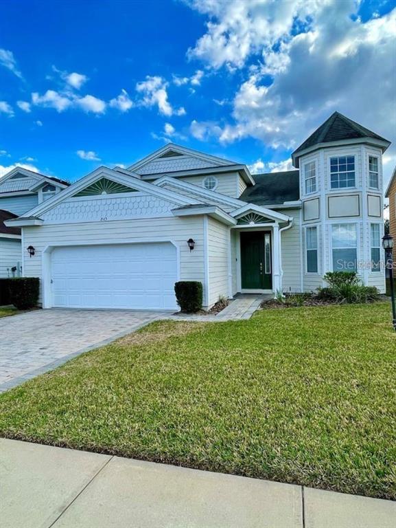 A two-story house with light-colored siding, a two-car garage, and a prominent corner turret — 2185 VICTORIA DRIVE, DAVENPORT, FL
