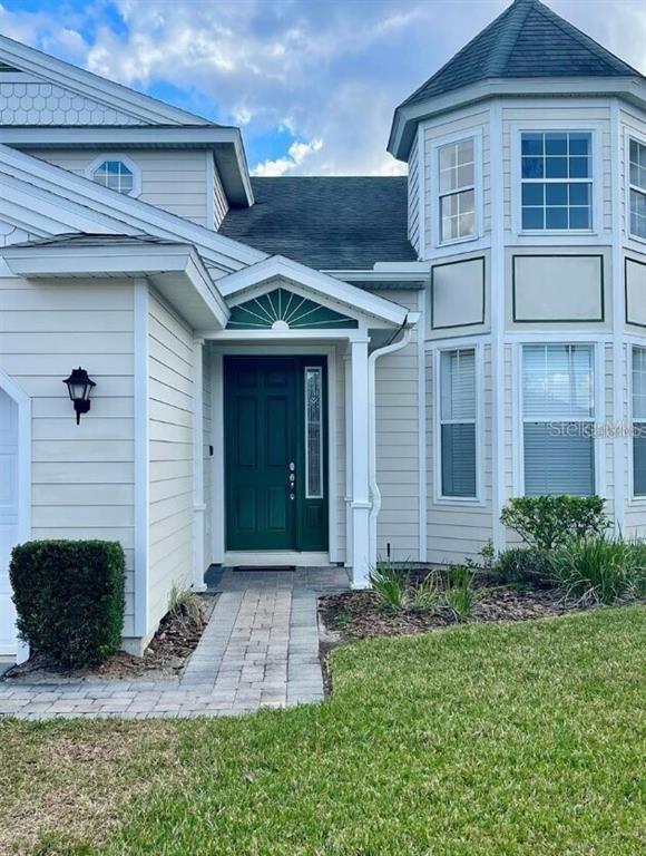 The exterior of a house features light-colored siding, a green front door, and a turret — 2185 VICTORIA DRIVE, DAVENPORT, FL