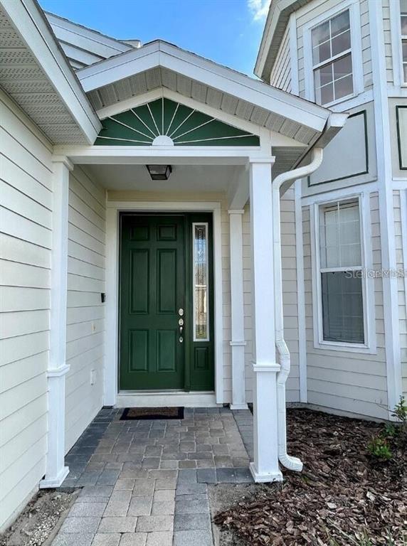 The exterior of a house features a green front door under a covered entryway — 2185 VICTORIA DRIVE, DAVENPORT, FL