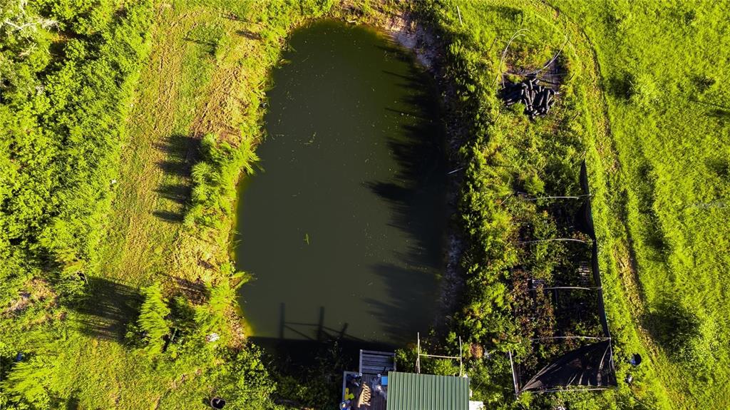 An aerial view shows a pond next to a small structure and a garden area — 34400 SR-62, PARRISH, FL