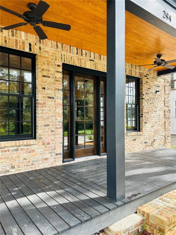A covered porch features a dark wood deck, brick walls, and two ceiling fans — 294 NW 12TH AVENUE, GAINESVILLE, FL
