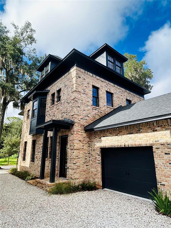 A three-story brick house features a black garage door and dark-framed windows under a blue sky — 294 NW 12TH AVENUE, GAINESVILLE, FL