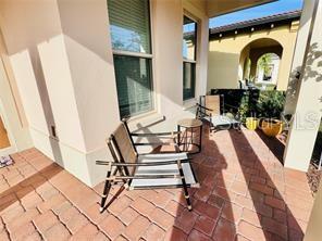 A patio with brick pavers features a modern chair, a small side table, and plants — 15155 CANOE PLACE, WINTER GARDEN, FL