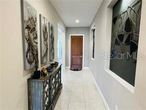 A hallway features light tile flooring, a wooden front door, and decorative wall art — 15155 CANOE PLACE, WINTER GARDEN, FL