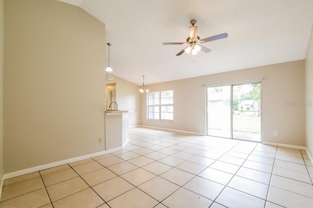 An open-concept living and dining area features beige walls, tile flooring, and a ceiling fan — 2854 CAMOMILE DRIVE, ORLANDO, FL