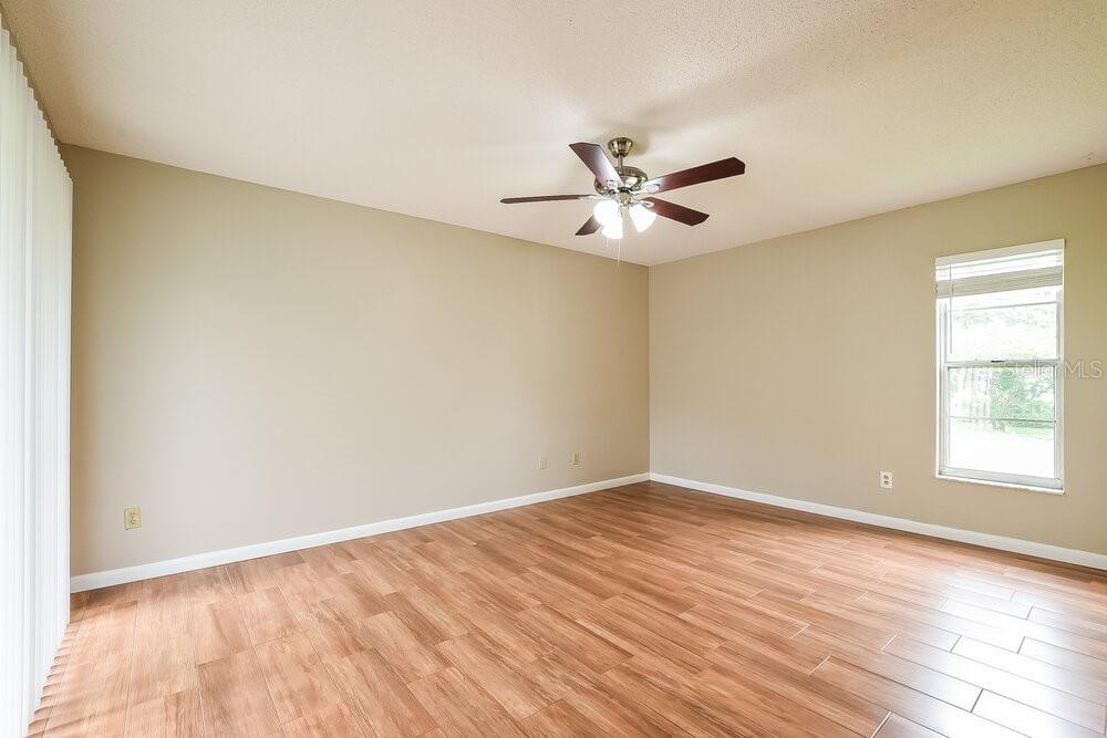 An empty room with light-colored walls, wood-look flooring, a ceiling fan, and a window — 2854 CAMOMILE DRIVE, ORLANDO, FL