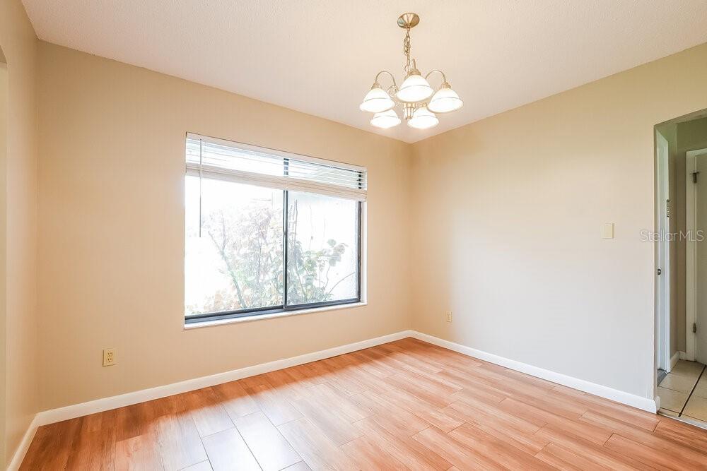 A dining room with light beige walls, wood-look flooring, a window, and a chandelier — 2854 CAMOMILE DRIVE, ORLANDO, FL