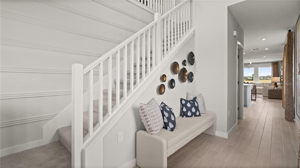 A staircase with white railings sits beside a bench and wall decor in a hallway — 1964 DIAMOND HEAD CIRCLE, LAKE HAMILTON, FL
