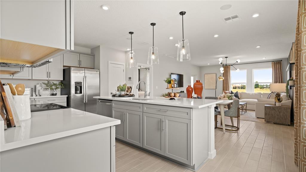 A kitchen with a large island and stainless steel appliances opens into a living area — 1964 DIAMOND HEAD CIRCLE, LAKE HAMILTON, FL