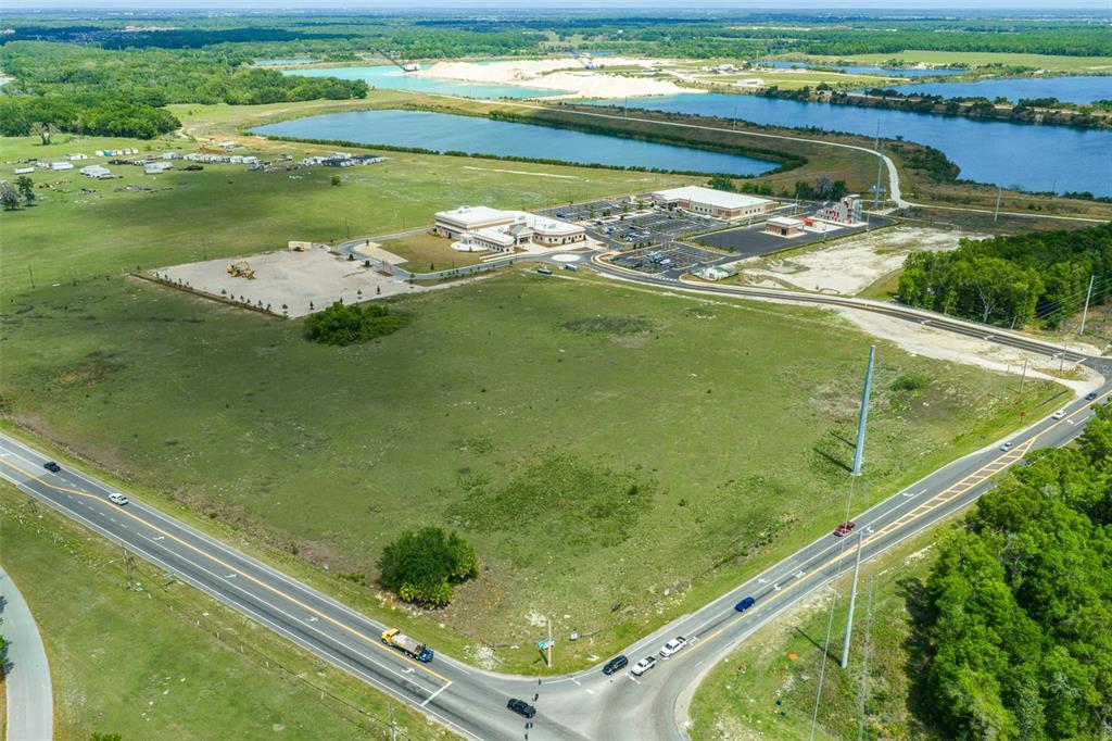 An aerial view shows a large, undeveloped grassy lot next to a commercial building complex — 178 N US 301, SUMTERVILLE, FL