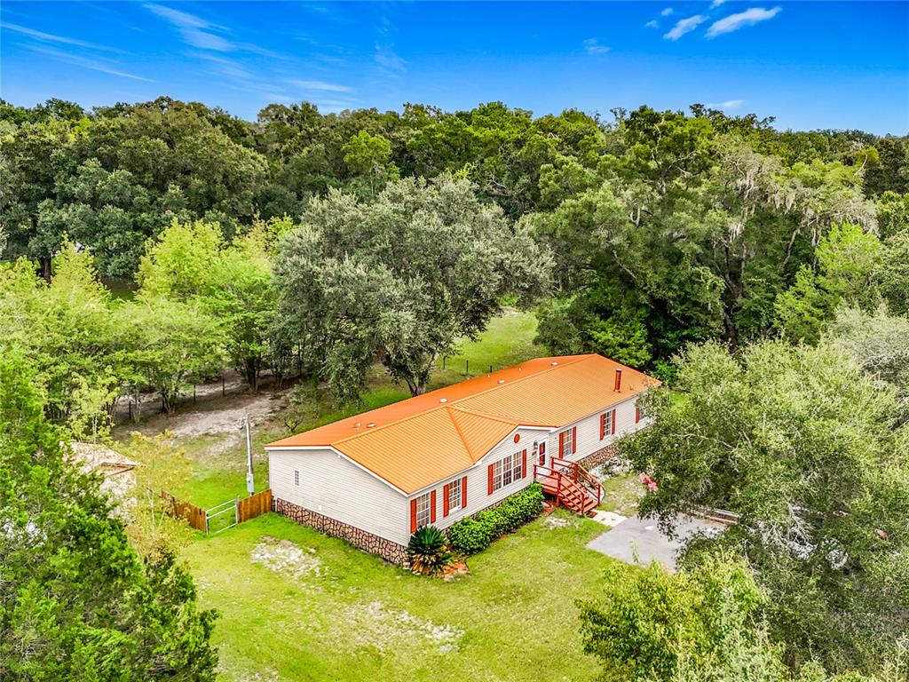 An aerial view of a single-story house with a bright orange metal roof — 13906 SW 132ND PLACE, ARCHER, FL