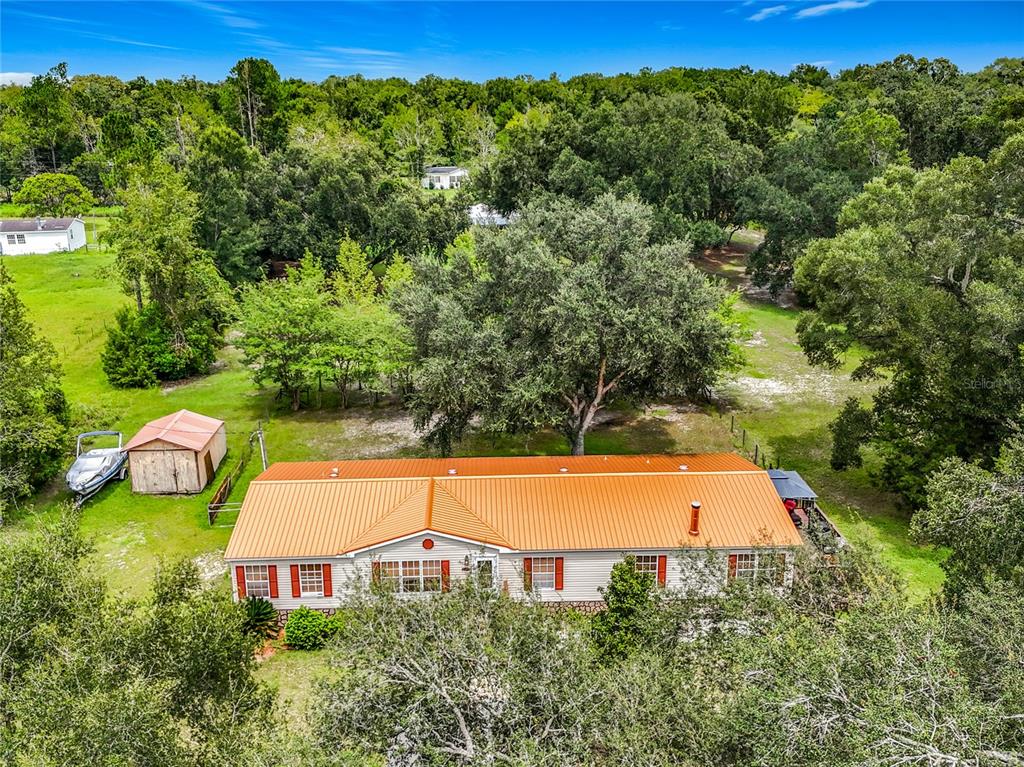 An aerial view of a single-story house with an orange metal roof and red shutters — 13906 SW 132ND PLACE, ARCHER, FL