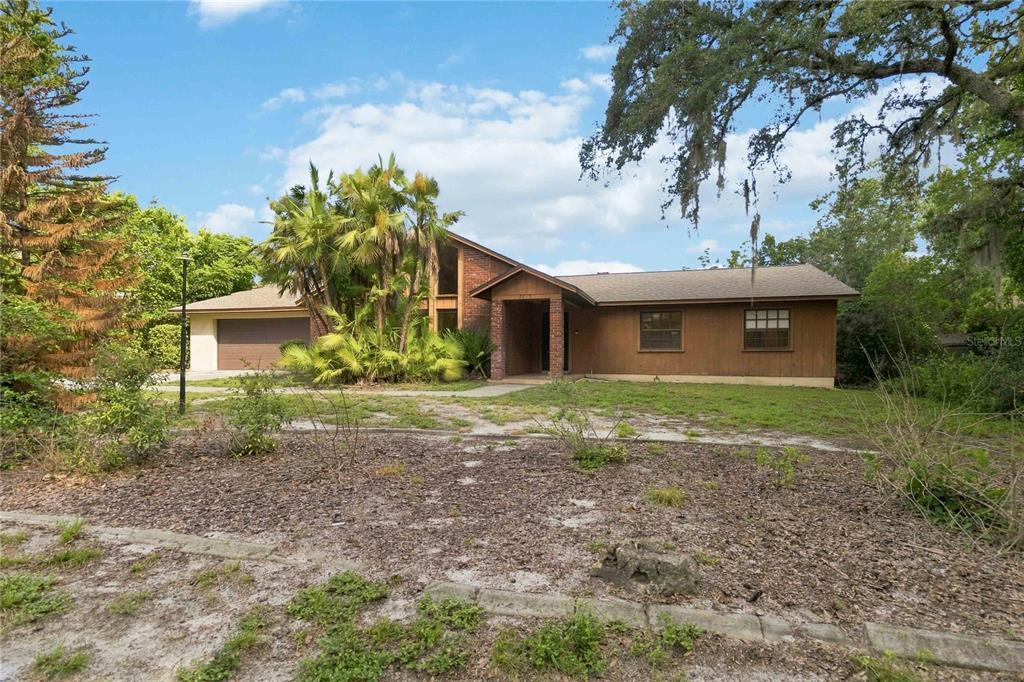 A single-story house with a brick facade, wood siding, and a large palm tree — 7813 SARANAC COURT, ORLANDO, FL