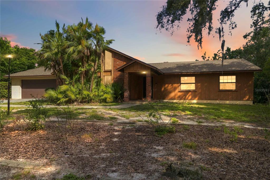 A single-story house with wood siding, a brick entryway, and palm trees at sunset — 7813 SARANAC COURT, ORLANDO, FL