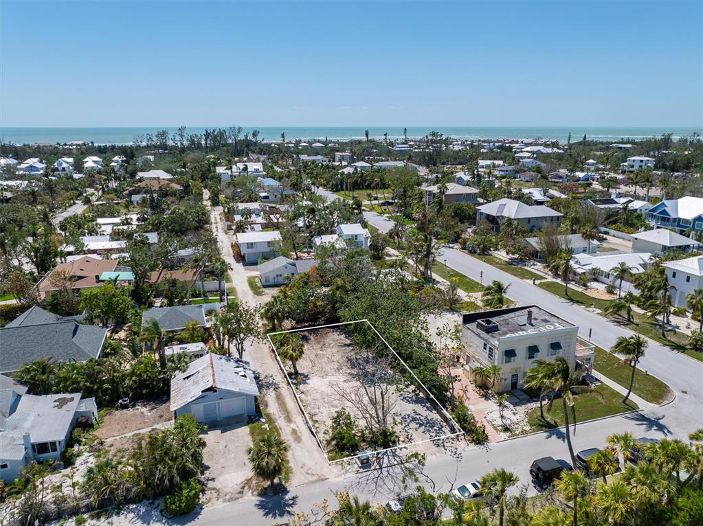 An aerial view shows a vacant rectangular lot situated between two houses near the coast — 6981 LOIS AVENUE, LONGBOAT KEY, FL