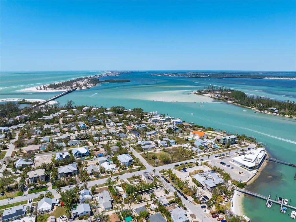 An aerial view shows a vacant residential lot in a coastal neighborhood near the water — 6981 LOIS AVENUE, LONGBOAT KEY, FL