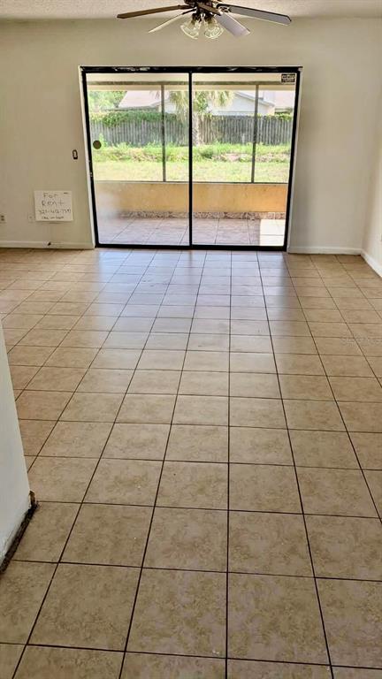 An interior room with beige tile flooring and a large sliding glass door to a patio — 1077 BASQUE DRIVE, ROCKLEDGE, FL