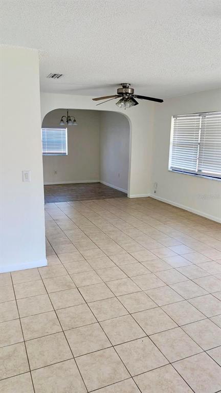 An open-concept living area features light-colored tile flooring, white walls, and an arched entryway — 1077 BASQUE DRIVE, ROCKLEDGE, FL