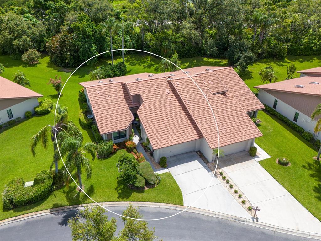 An aerial view shows a single-story house with a tiled roof and a concrete driveway — 4004 WILSHIRE CIRCLE E UNIT 89, SARASOTA, FL