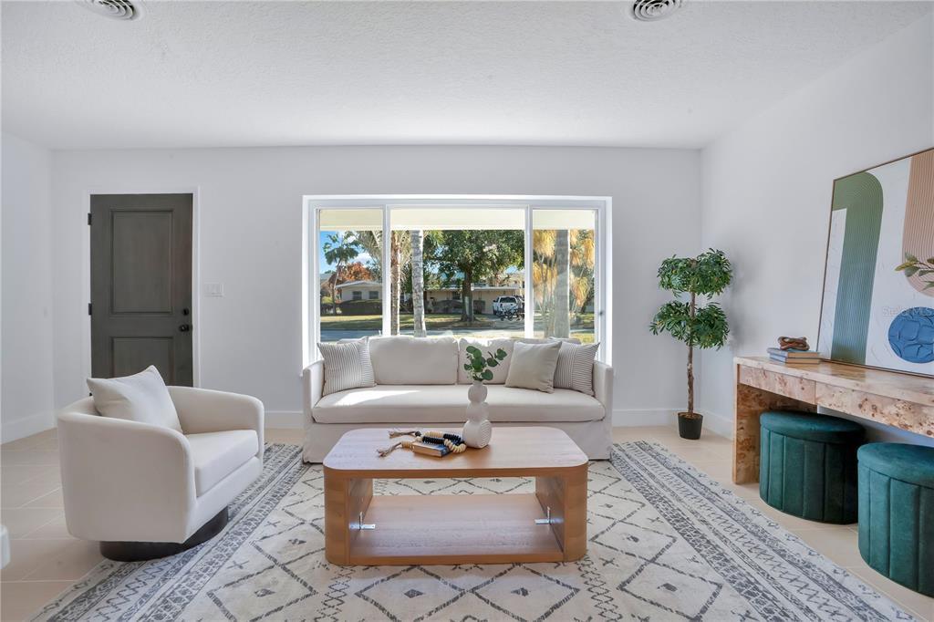 A living room features a white sofa, a wooden coffee table, and a swivel armchair — 2801 GULFSTREAM ROAD, ORLANDO, FL