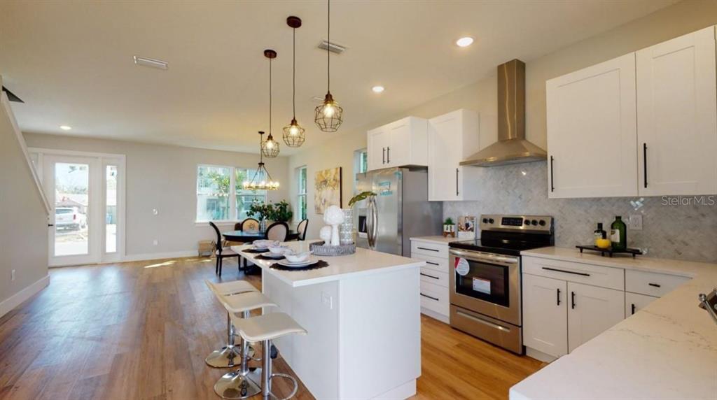 A modern kitchen features white cabinets, stainless steel appliances, a center island, and pendant lighting — 5113 12TH AVENUE N, ST PETERSBURG, FL