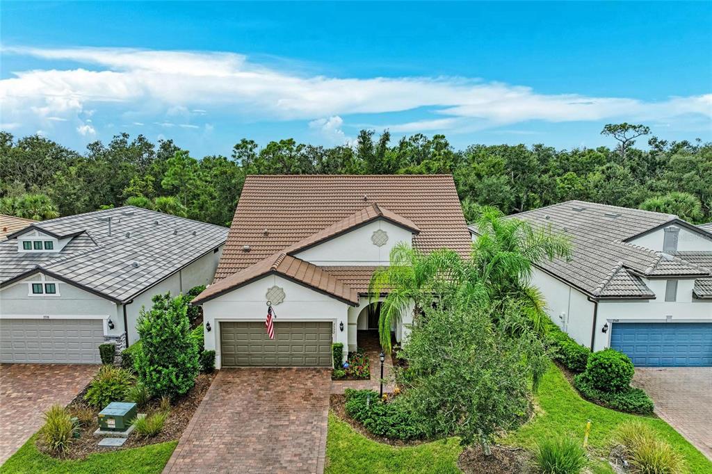 An aerial view of a suburban house with a brown tile roof and brick driveway — 7572 VIOLA LOOP, BRADENTON, FL