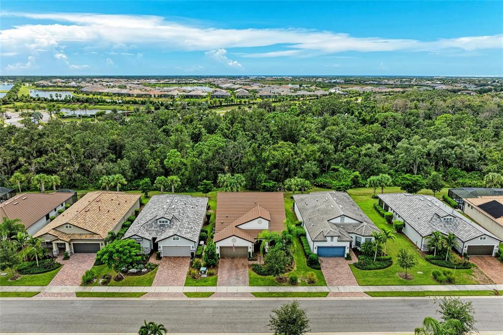An aerial view shows a row of suburban houses with tiled roofs and paved driveways — 7572 VIOLA LOOP, BRADENTON, FL