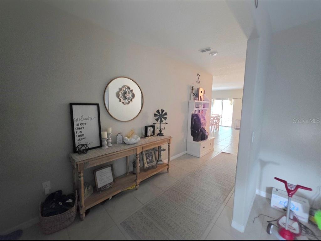 A hallway features a wooden console table, a round mirror, and a white entryway bench — 1561 FLOWER DUST DRIVE, RUSKIN, FL