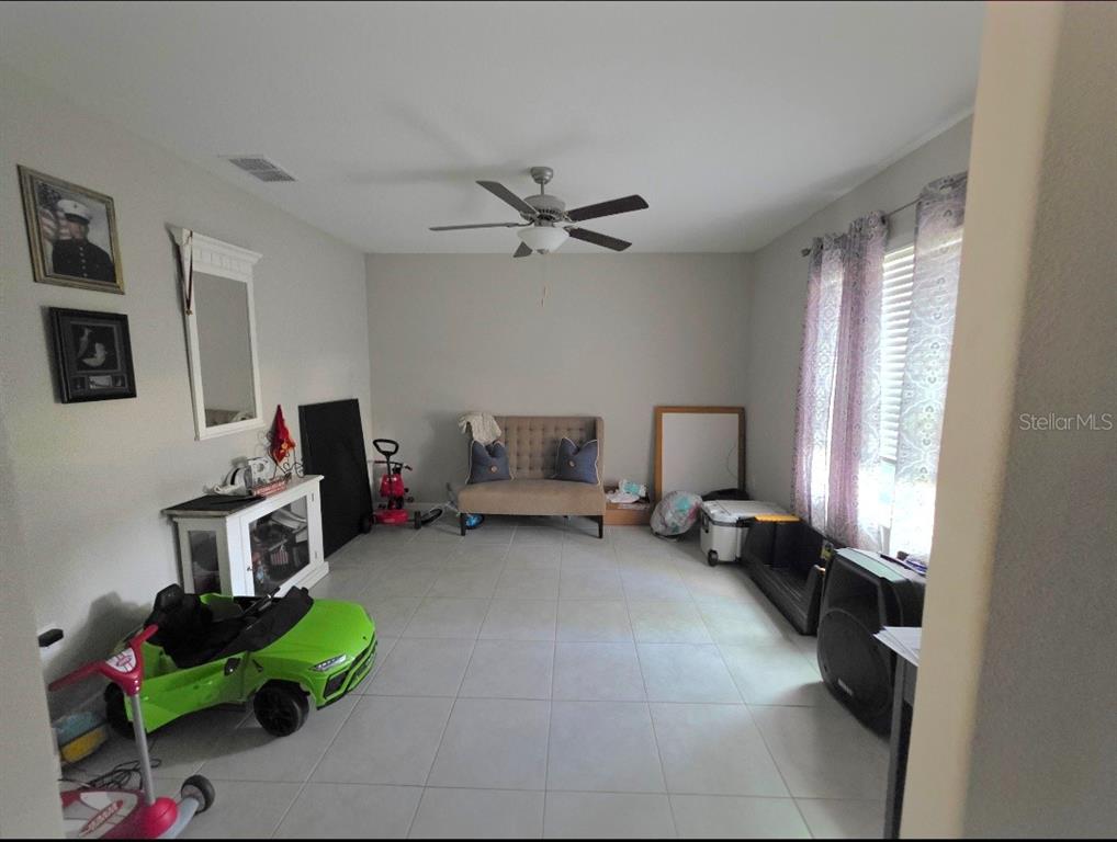 A room with light-colored tile flooring, a ceiling fan, and a small tufted loveseat — 1561 FLOWER DUST DRIVE, RUSKIN, FL