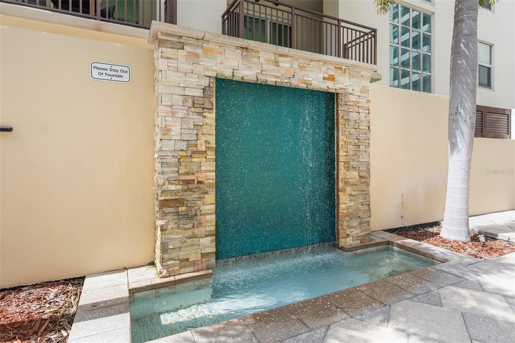 A stone-clad water feature with a small pool sits against a beige exterior wall — 1238 E KENNEDY BOULEVARD UNIT 501, TAMPA, FL