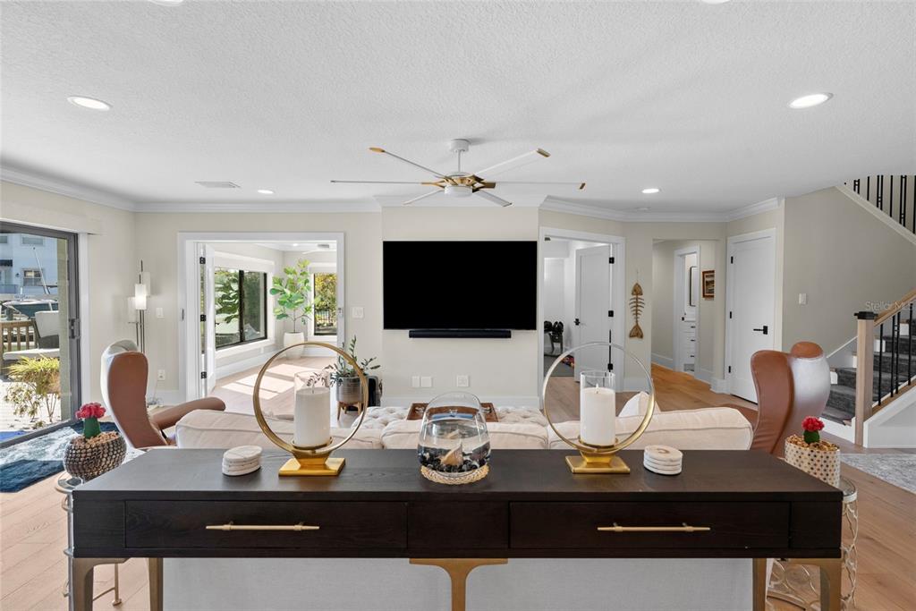 A living room features a dark wood console table, white sofa, and a wall-mounted television — 4926 W MELROSE AVENUE N, TAMPA, FL