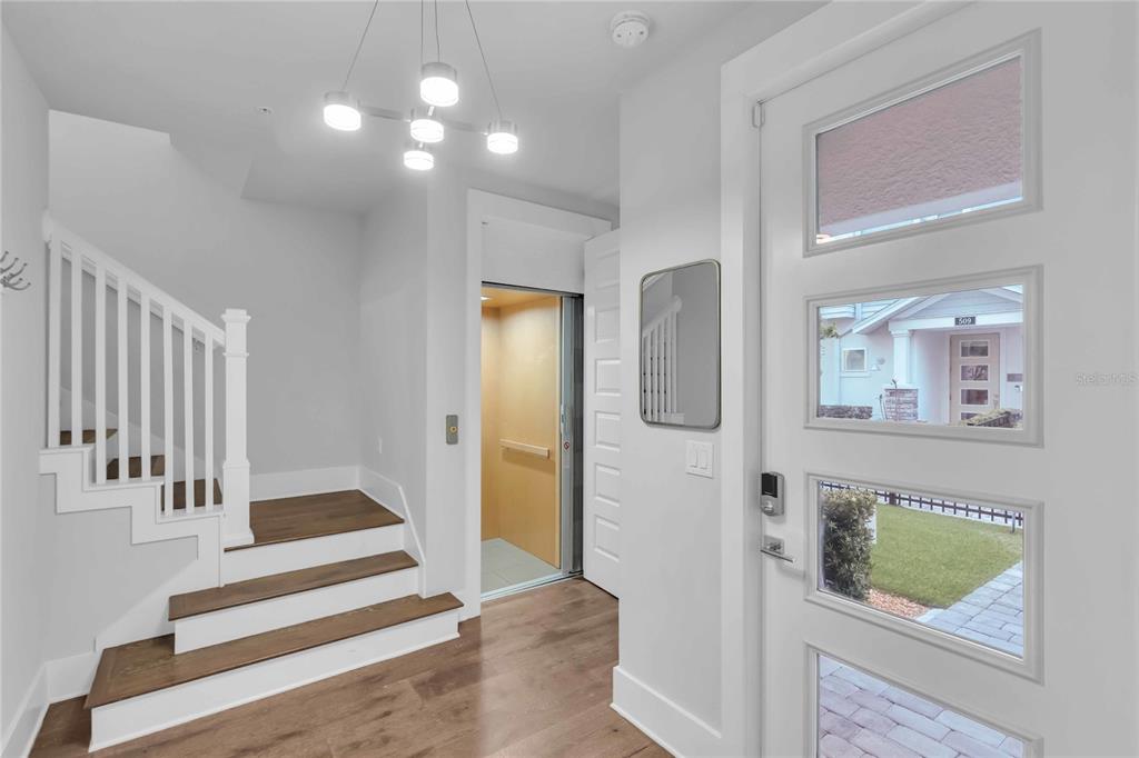 An entryway features a wooden staircase, a residential elevator, and a white front door — 506 LAUREL PARK DRIVE UNIT 506, SARASOTA, FL