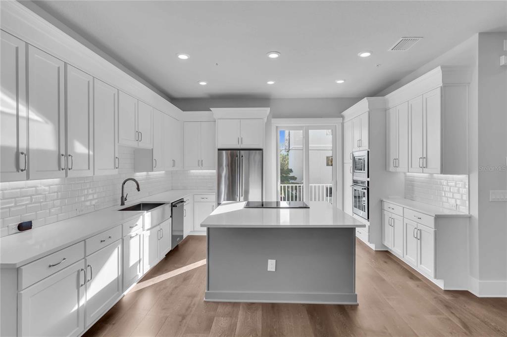 A modern kitchen features white cabinetry, a gray center island, and light wood flooring — 506 LAUREL PARK DRIVE UNIT 506, SARASOTA, FL