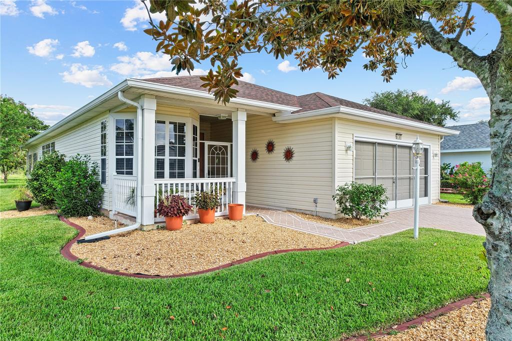 A one-story house with light yellow siding, a front porch, and a paved driveway — 4738 ST ANDREWS ARCADE, LEESBURG, FL