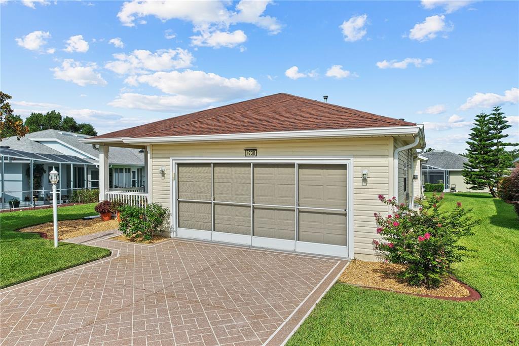 A beige detached garage with a screen door and a patterned concrete driveway — 4738 ST ANDREWS ARCADE, LEESBURG, FL