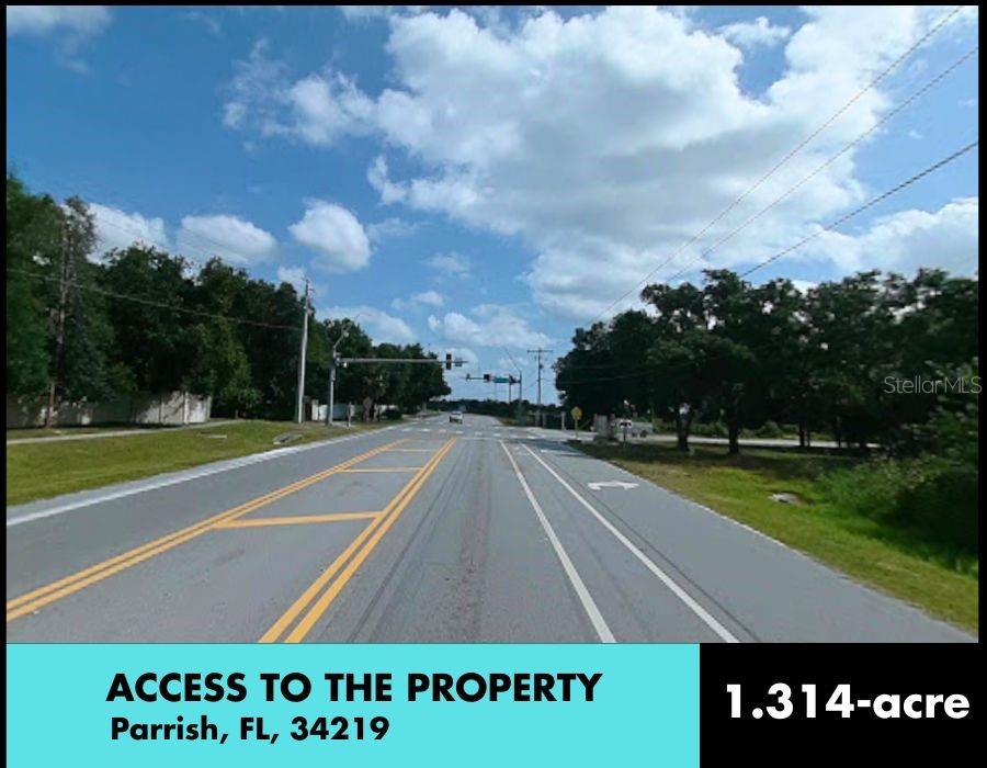 A view of a paved road leading toward a traffic light intersection with surrounding trees — 2426 FORT HAMER ROAD, PARRISH, FL