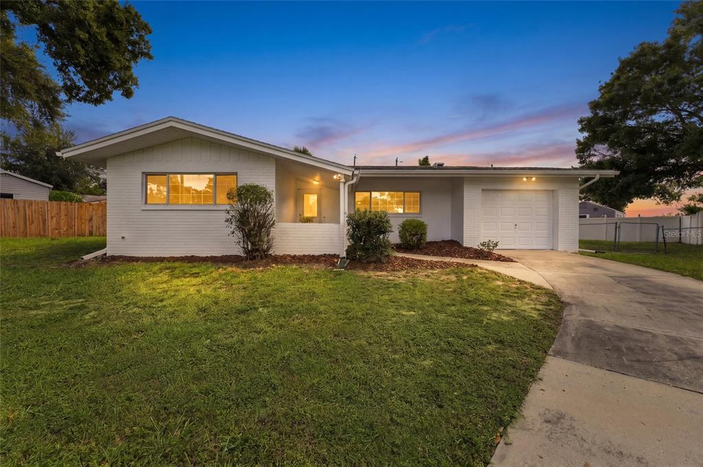 A single-story white brick house with a garage and a front lawn at dusk — 1773 LONDON LN, CLEARWATER, FL