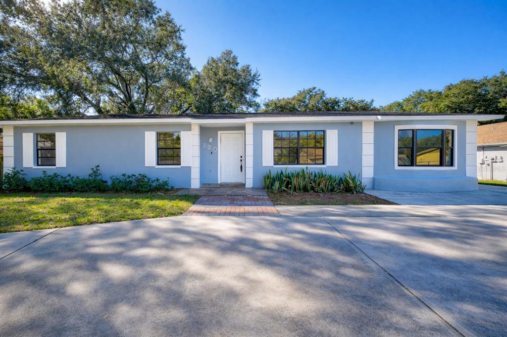 A single-story gray house with white shutters and a concrete driveway under large oak trees — 720 SWISS DRIVE, LAKELAND, FL