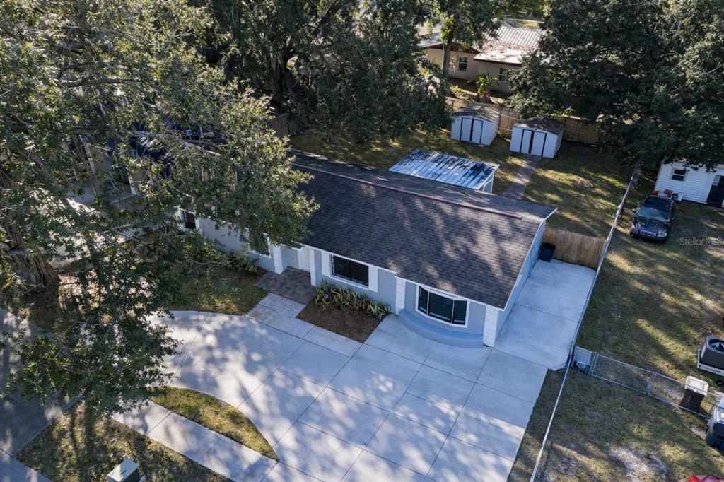 An aerial view shows a blue single-story house with a large concrete driveway and lawn — 720 SWISS DRIVE, LAKELAND, FL