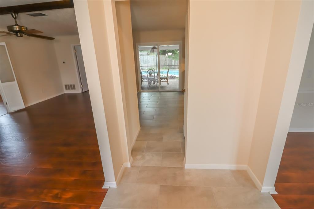 A tiled hallway leads from a wood-floored room to a patio with a swimming pool — 3442 RED OAK CIRCLE E, ORANGE PARK, FL
