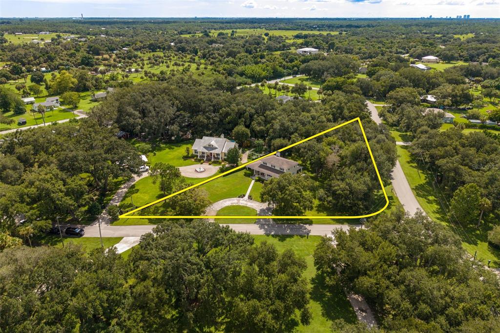 An aerial view shows a house on a large, tree-filled lot outlined in yellow — 4691 LONG LAKE DRIVE, FORT MYERS, FL
