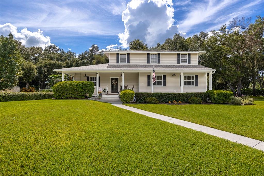 A two-story house with light siding, a covered front porch, and a large green lawn — 4691 LONG LAKE DRIVE, FORT MYERS, FL