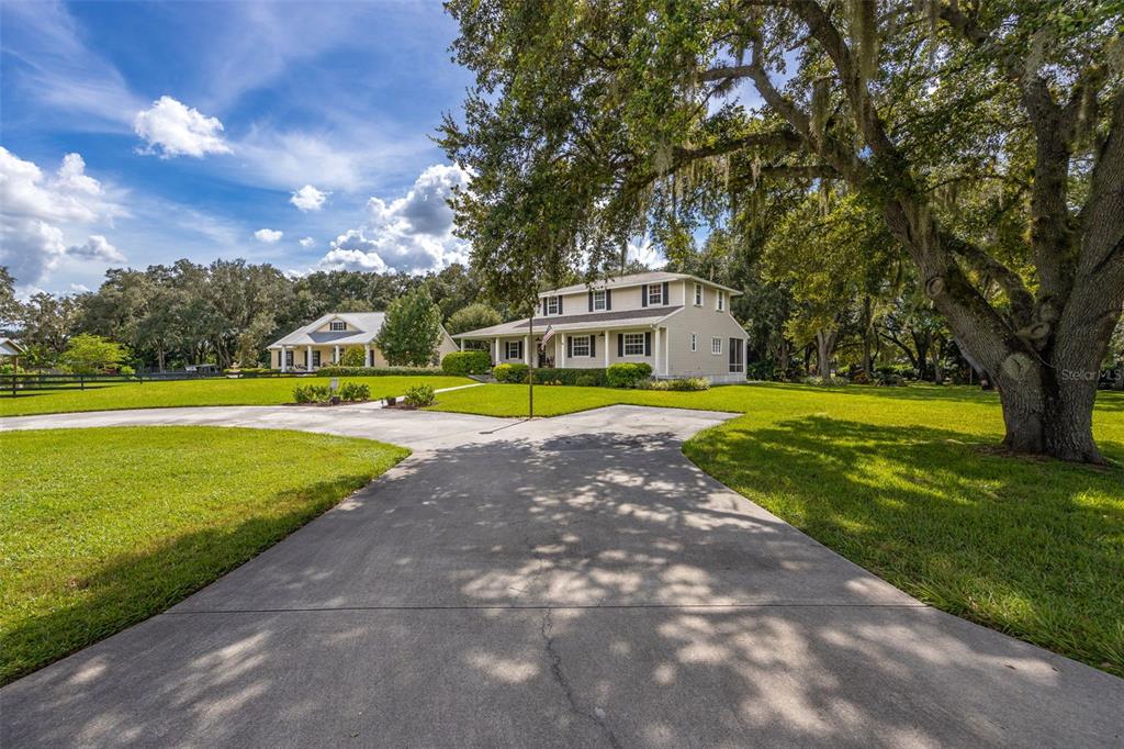 A two-story house with a driveway and large oak trees on a grassy lot — 4691 LONG LAKE DRIVE, FORT MYERS, FL
