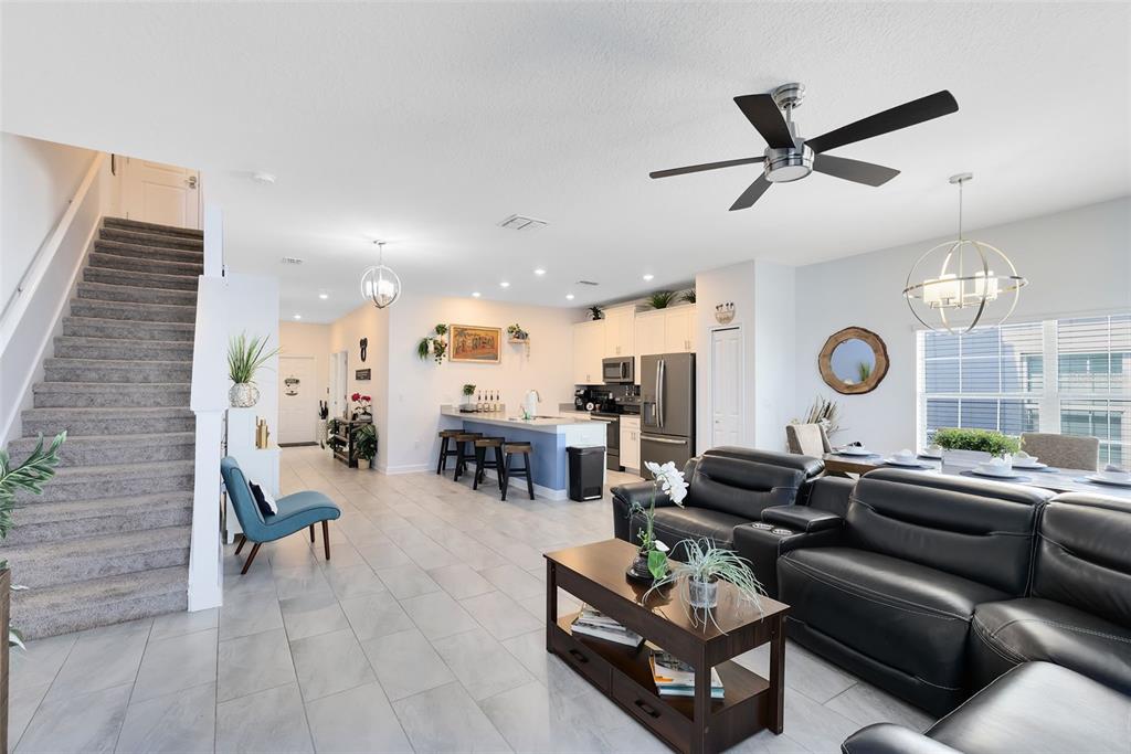 An open-concept living room and kitchen feature tile flooring, a staircase, and modern furnishings — 1575 SANDBAGGER DRIVE, DAVENPORT, FL